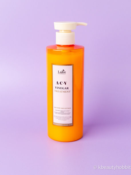 Orange pump bottle of La'dor ACV Vinegar Treatment on a lavender background, labeled for shine and softness.