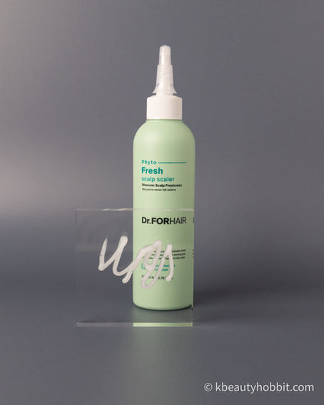 A green bottle of Phyto Fresh Scalp Scaler by Dr.FORHAIR on a gray backdrop. White gel squiggle on a transparent card in front.