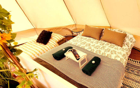 A bell tent with fixed double bed and extra single mattress for luxury glamping in Nottinghamshire
