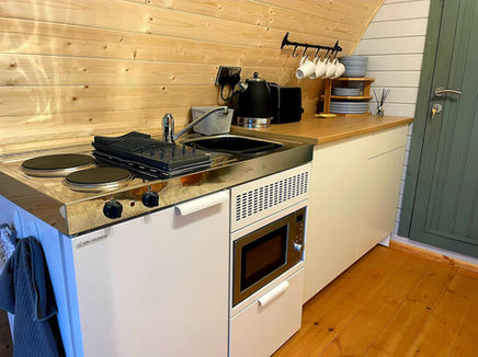 Kitchen and fold-out dining table in the luxury three-person glamping pod at BrackenXcapes