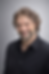 Portretfoto van Joost Oosterwijk met krullend haar, baard en donkere blouse tegen een grijze achtergrond.