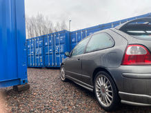 sports car next to a row of shipping containers