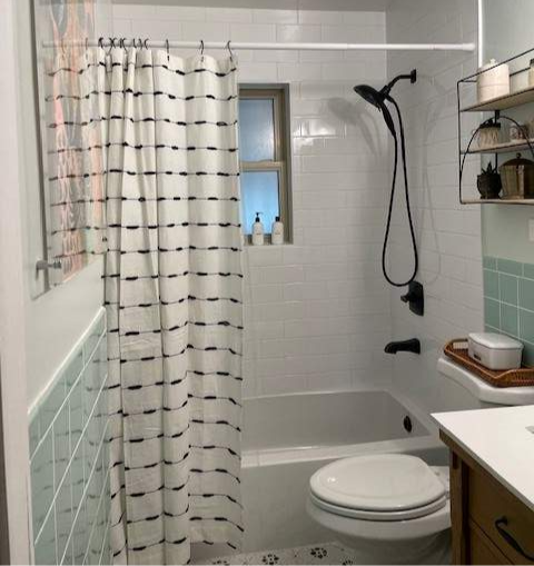 new bathroom with green tile and shower curtain