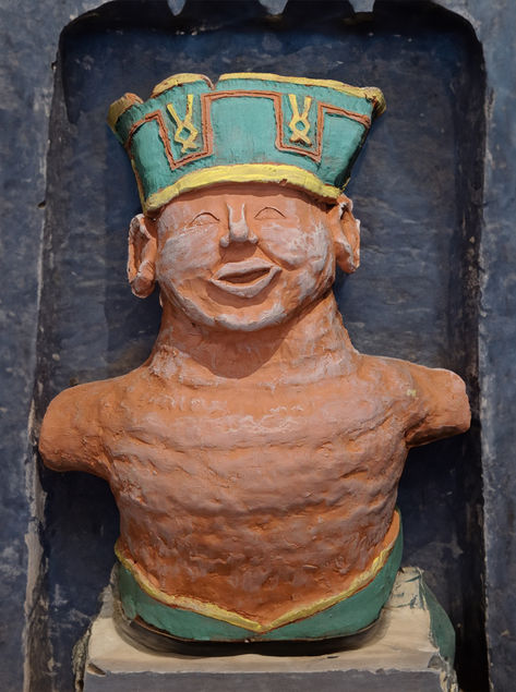 a photo of a ceramic stature of the torso of a smiling man with a green and yellow headdress