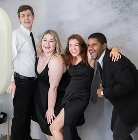 Group of friends at a wedding enjoy taking a picture together with a photo booth.