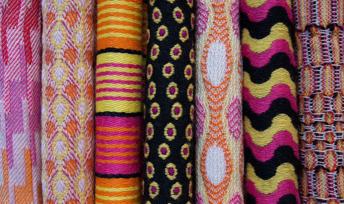 A collection of seven handwoven fabrics. Various combinations of orange, yellow, pink and black Worsted spun wool are woven into geometric and patterned weave techniques. All woven on a twenty-four shaft Compu-Dobby AVL studio loom. Textiles and homewares handwoven by Stephanie Pfister in Wiltshire, UK.