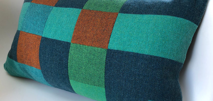 Handwoven cushion in Merino Lambswool using four colours; light blue, dark blue, orange and green .A double weave structure woven on a 16 shaft floor loom. Backing handwoven in teal Merino Lambswool in double weave. Back zip closure. Feather cushion pad. Textiles handwoven by Sue Hopkinson in the UK.
