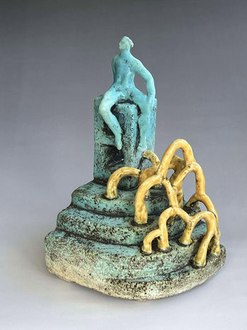 New in store August 2025; small ceramic sculpture of a figure seated atop a hill with yellow brambles by Brendan Adams; link takes you to the product page for this artwork.