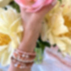 Hand holding peony flowers with bracelets made from pearls, peach moonstone, sakura agate and sandalwood