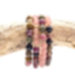 stack of beautiful bracelets displayed on a weathered wood branch created with pink tourmaline and muscovite