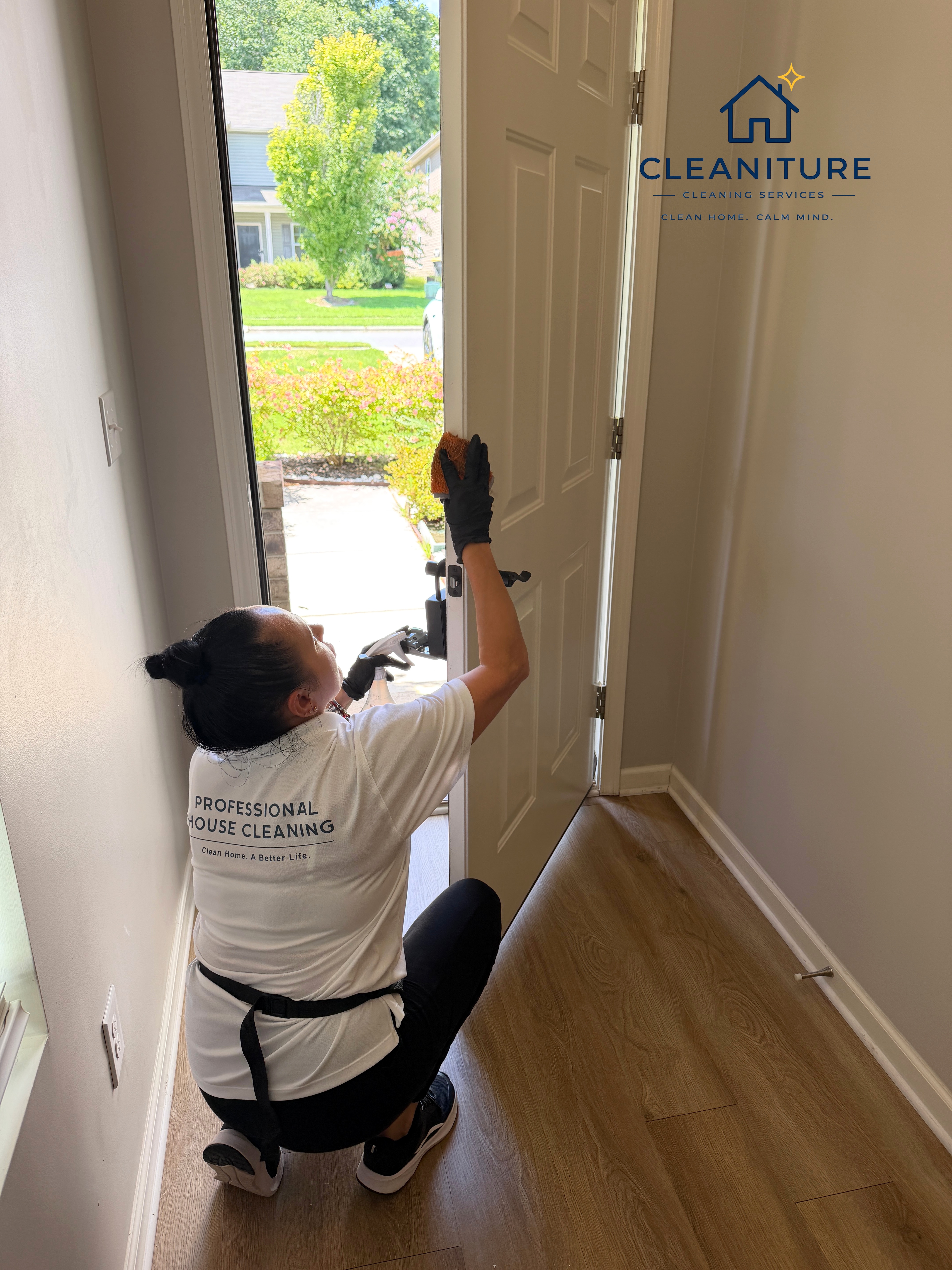 Professional house cleaner sanitizing a white front door in Cornelius, NC