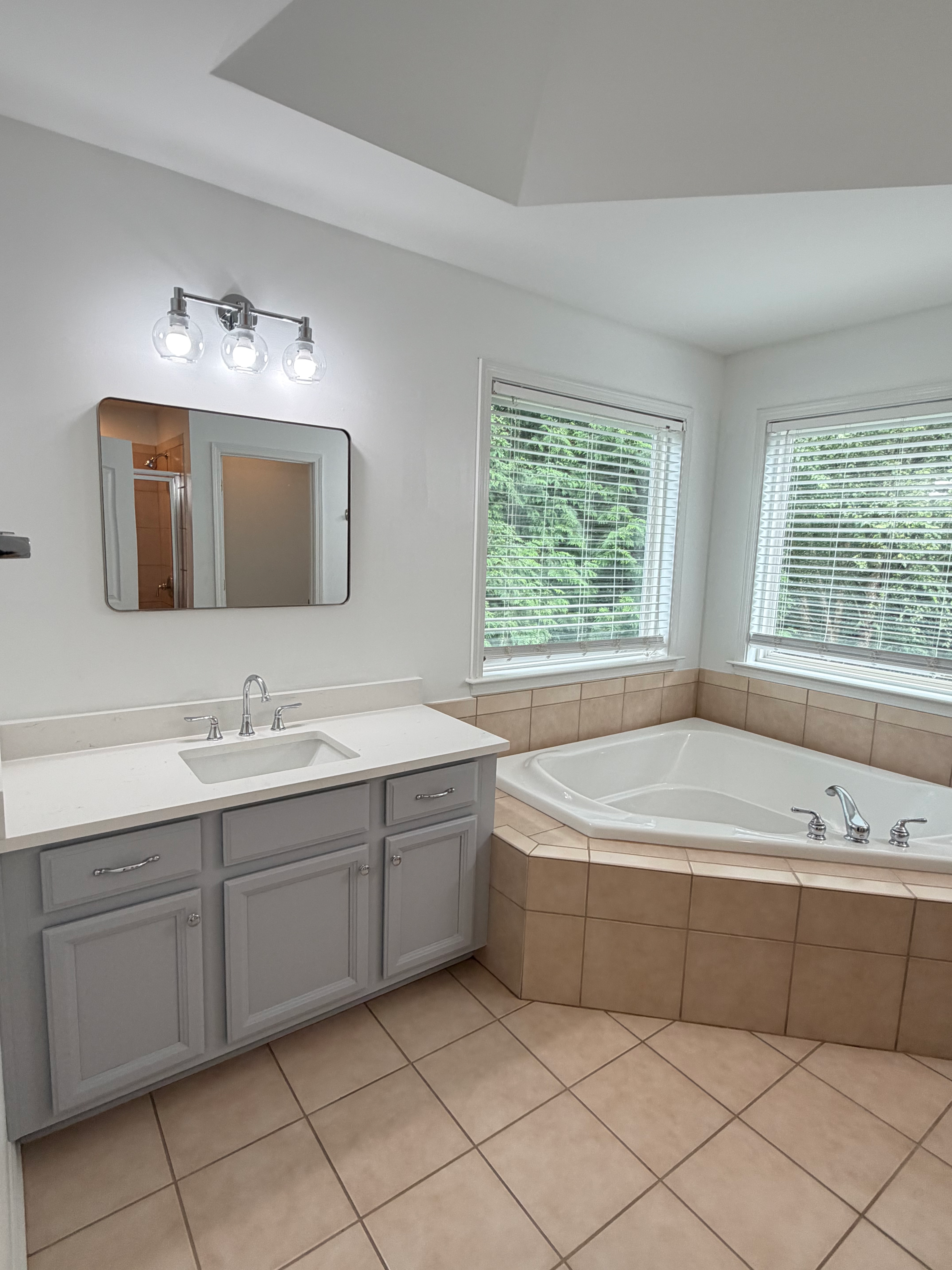 Modern bathroom with gray vanity and corner soaking tub in Huntersville, NC