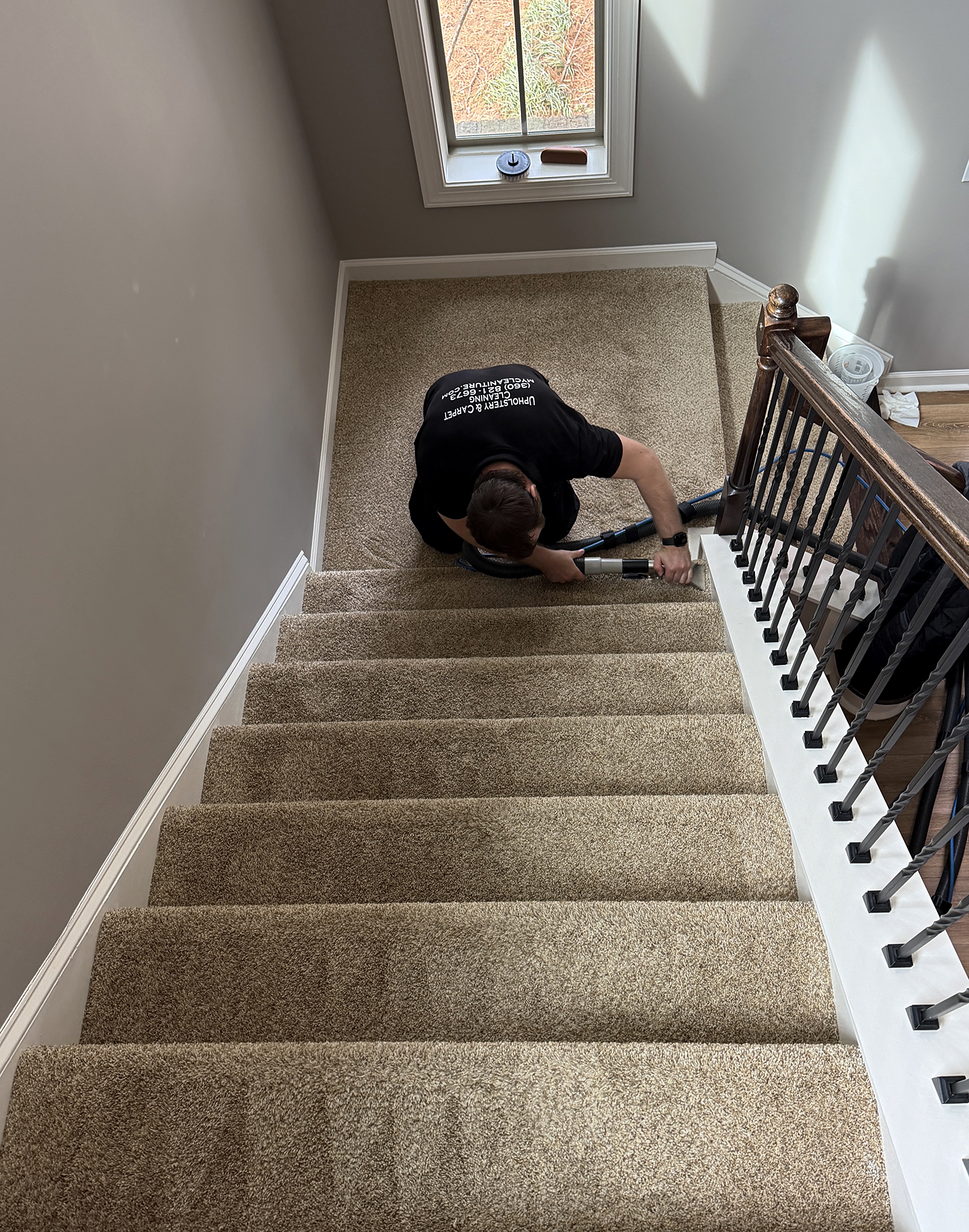 Technician deep cleaning carpeted stairs with a vacuum tool in Cornelius, NC
