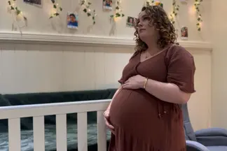 A pregnant Talitha Jae stands before a crib for an 'Ada' promo shot