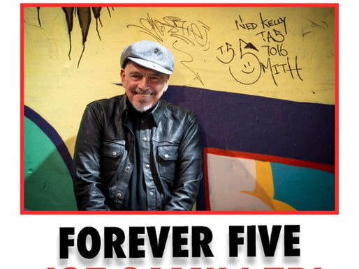 oe Camilleri — frontman of The Black Sorrows and Australian music legend — wearing a beret and leather jacket with a playful grin, standing before a graffitied wall. A portrait of timeless cool and decades of soul, blues and rock history.