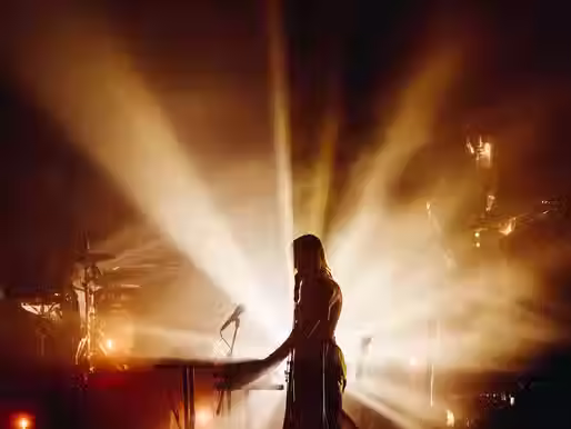 Sophie Payten (Gordi) singing passionately beneath a halo of stage lights during her ‘Like Plasticine’ tour performance.