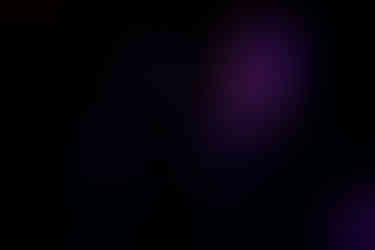 Carla Geneve performing onstage at QPAC Concert Hall, standing with an acoustic guitar under soft, warm lighting.