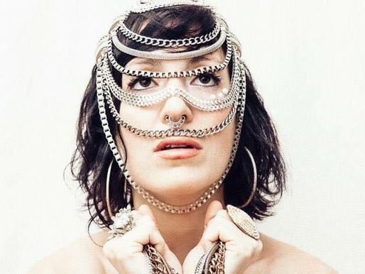 A female artist called Ladi Abundance posing for a promo pic, her face covered in jewels