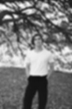 Singer, writer and producer, Ben Provest stands in leaves under a tree, but in black and white