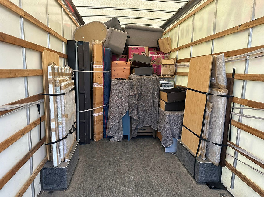 The interior of a moving truck packed with boxes, furniture, and covered items