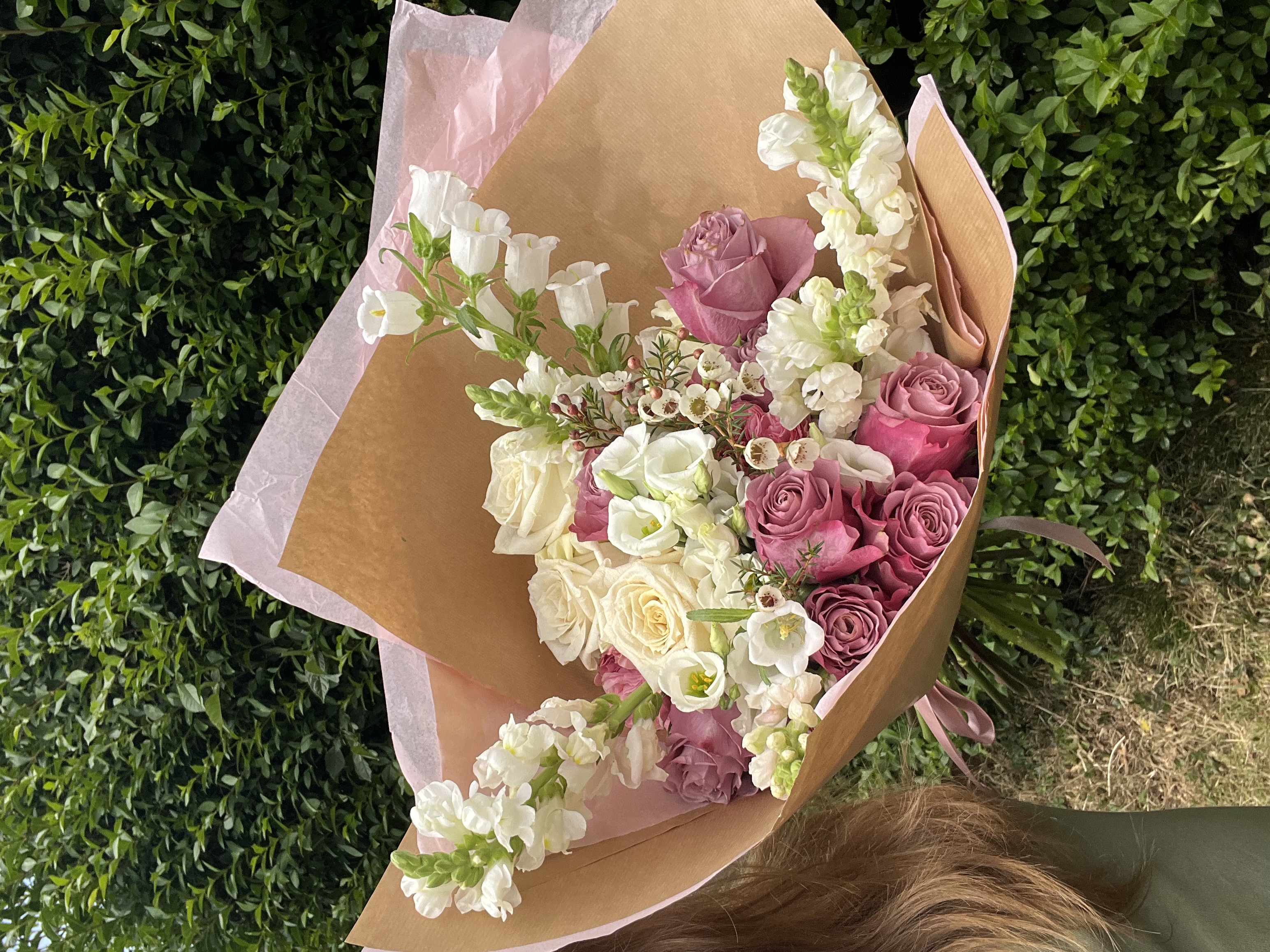 Wrapped bouquet of cream and pink flowers