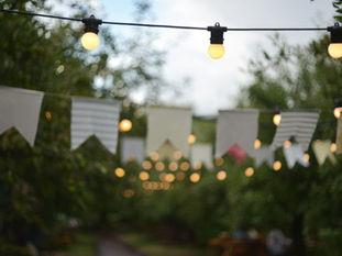 Imagen referencial de luces y banderines en una celebración al aire libre durante la noche.
