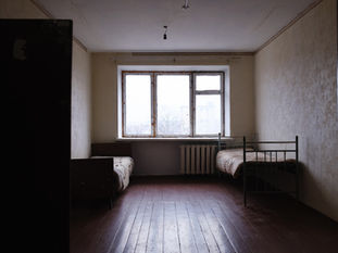 Habitación de albergue con dos camas preparadas junto a una ventana.