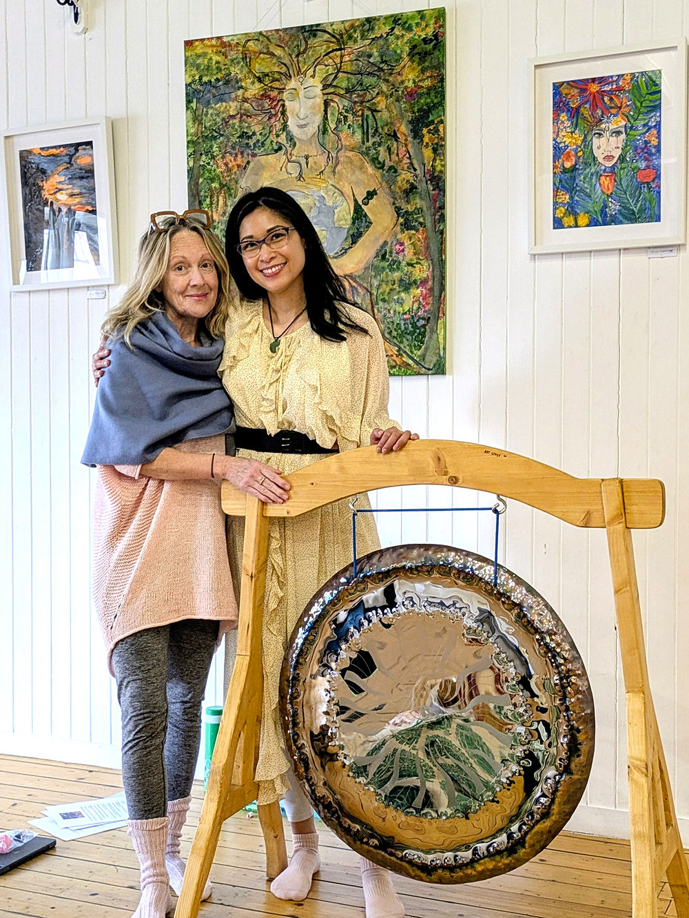 Two women standing close together near the gong