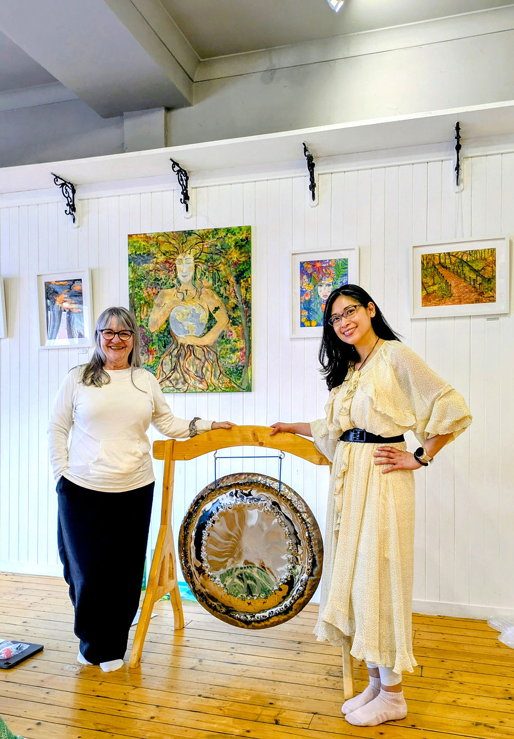 Two women standing on either side of the gong