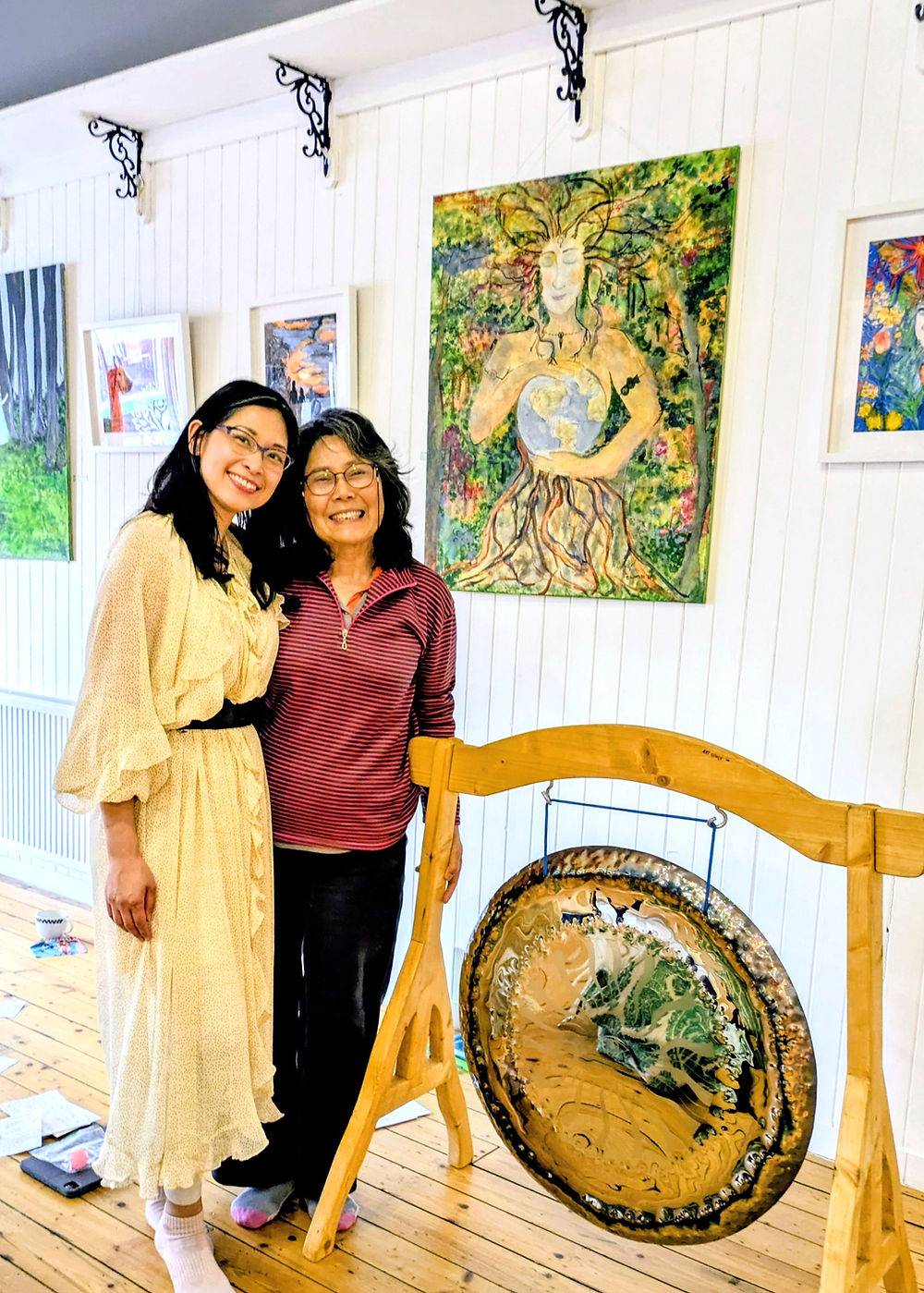 Two women standing together near a gong