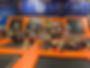 A group of children sitting on a trampoline court at an indoor trampoline court smiling at the camera during a field trip to Launch Pad Trampoline Park.
