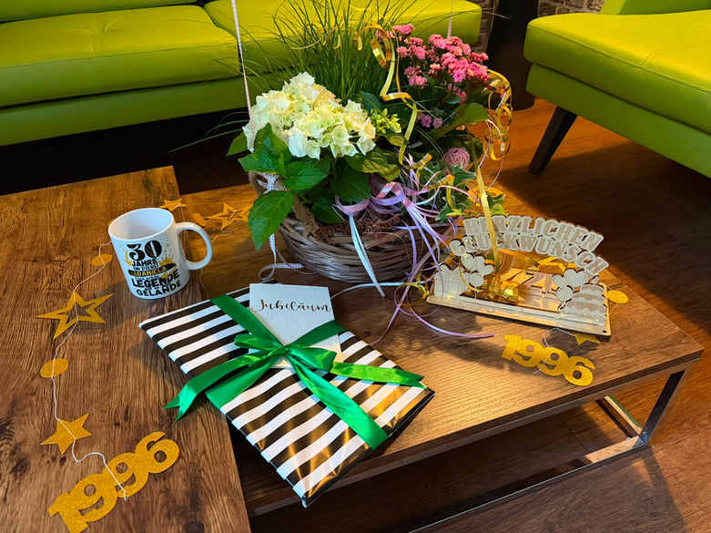 eier zum 30-jährigen Jubiläum von der examinierten Pflegekraft der Hauskrankenpflege Kossian: Goldene Ballons mit der Zahl 30, ein Blumenstrauß, eine Geschenk und kleine Geschenke auf einem stilvollen Tisch.