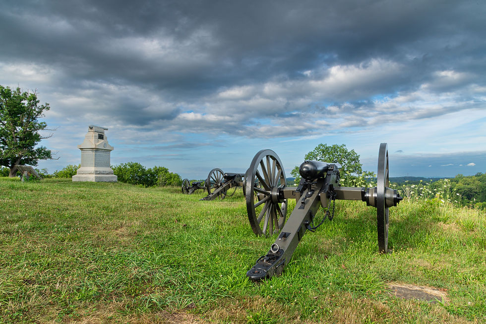 An image of the Gettysburg battlefield. Pictured is a cannon and a stone statue.