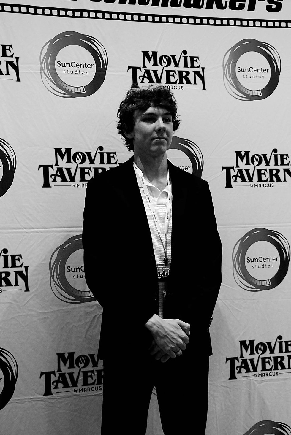 An image of director Theodore Linden standing on a red carp at a film festival. In the picture, he is wearing a suit with a white shirt under it.