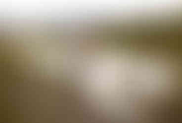A groom picks up his bride and she smiles back at him. They are standing next to the snake river in front of the grand teton mountain range.
