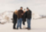 A family portrait of 4 people at the top of jackson hole mountain resort in the winter. The landscape is mountainous and covered in snow.