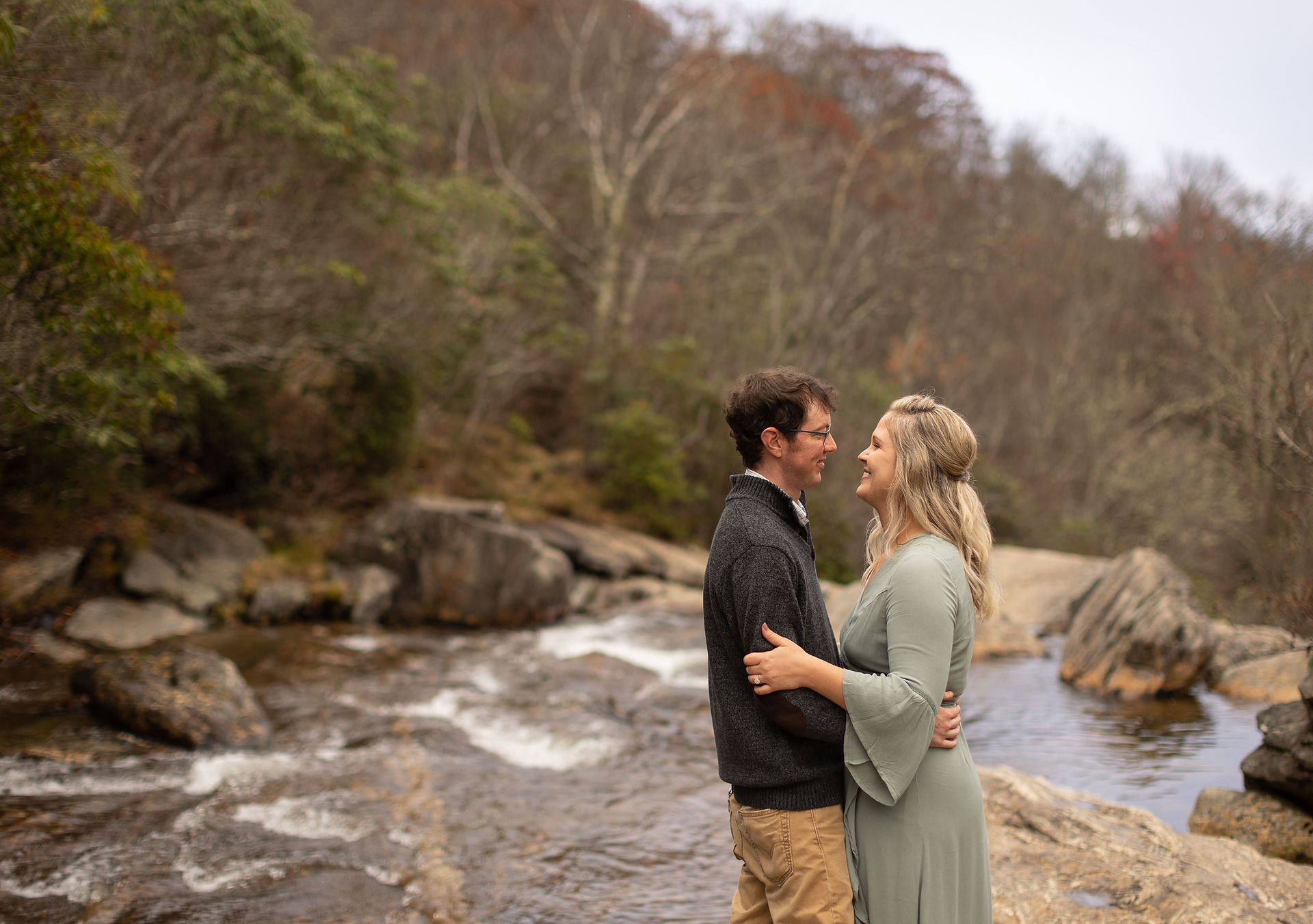 A couple holding each other close on a creek bed.