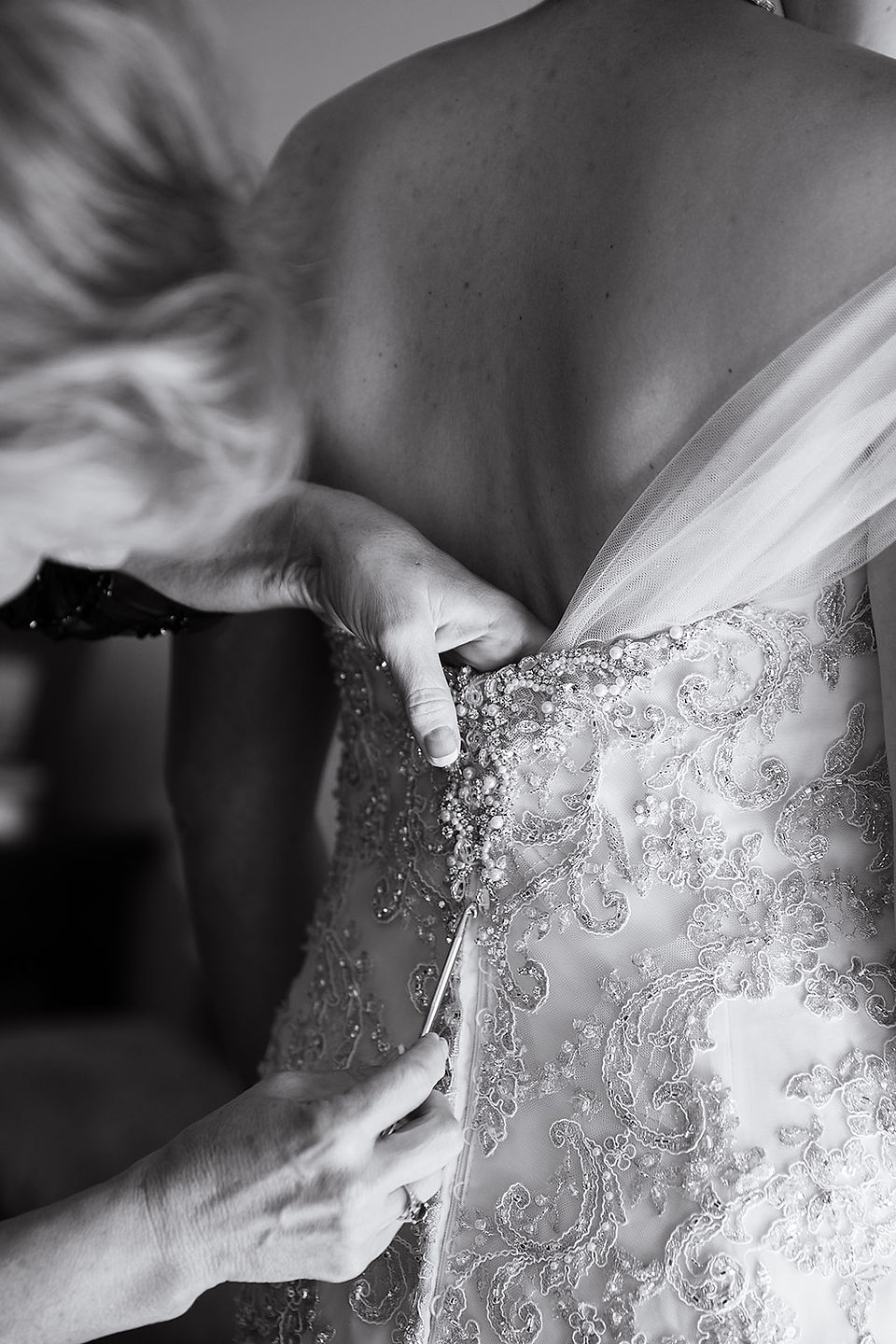bride putting finishing touches on the bride's dress 