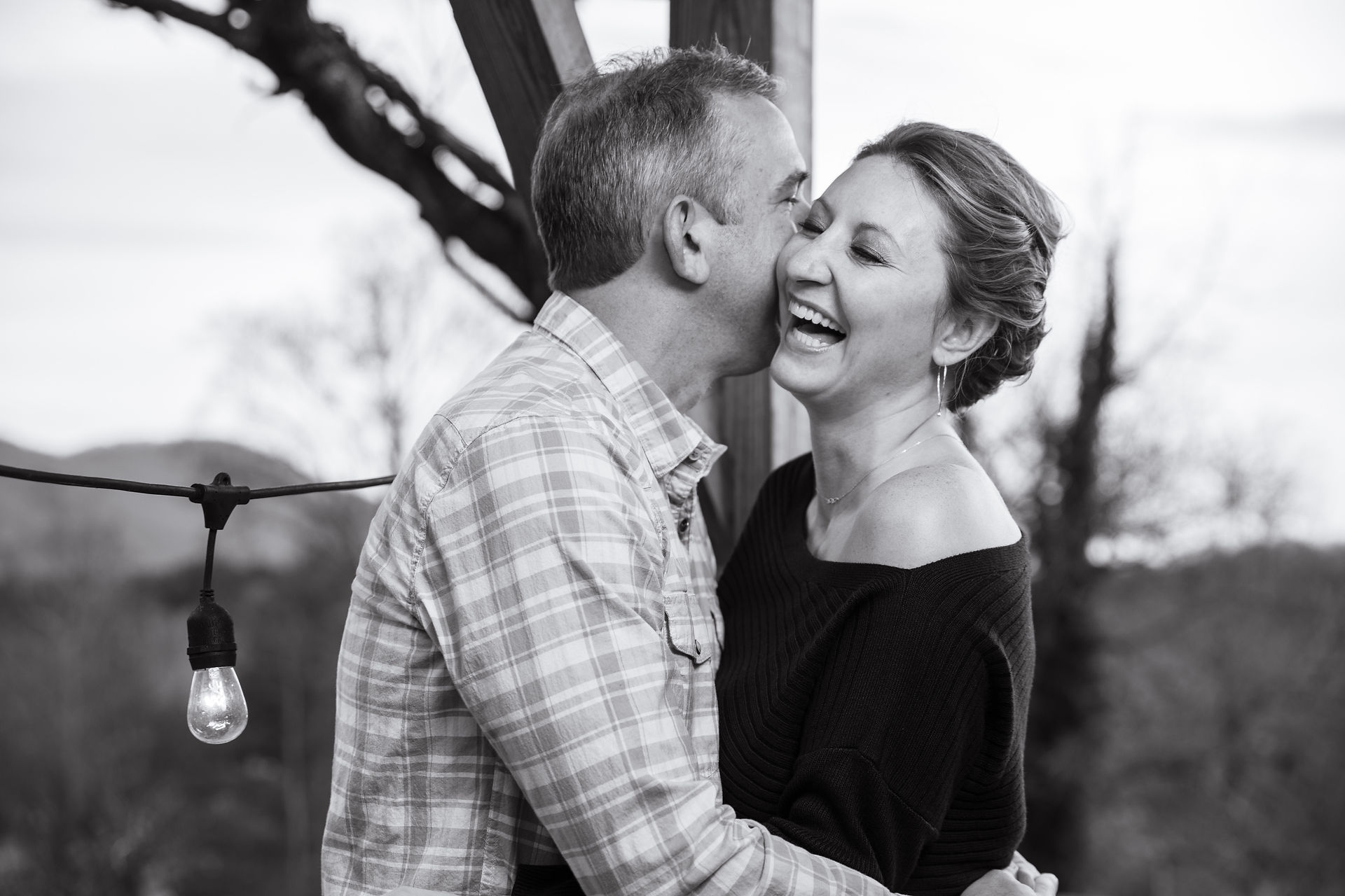 woman laughing as her fiance whispers in her ear 