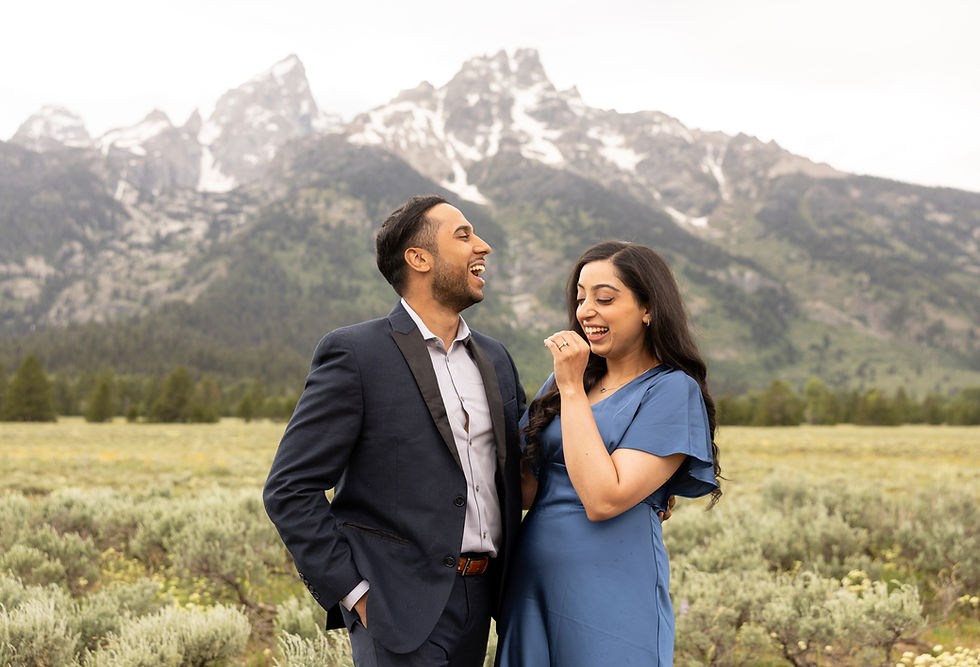 A newly engaged couple laughing as they hold each other close.