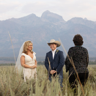 bride and groom smiling at each other in front of the grand tetons 