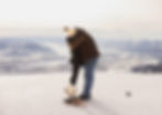 A couple hugs in celebration moments after their surprise proposal at the top of Jackson Hole Mountain Resort. The landscape is mountainous and covered in snow.