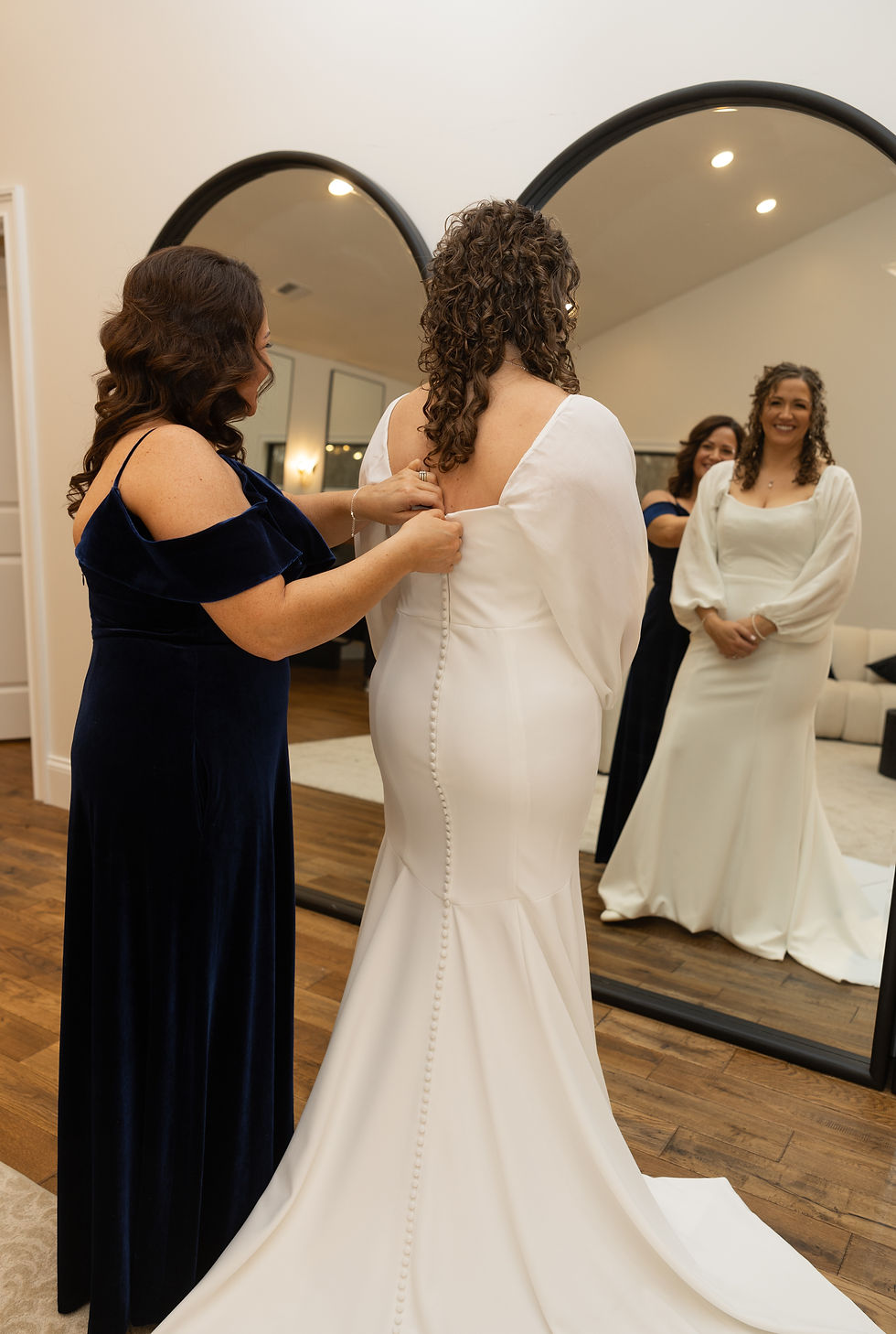 Maid of honor helping the bride button up her dress.