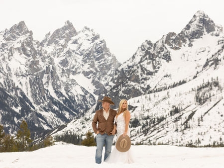 A bride and groom looking opposite directions in front of the snow covered grand tetons