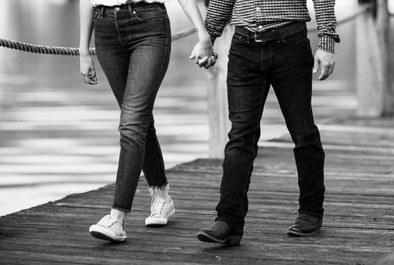 A couple's feet and hands on a board walk.