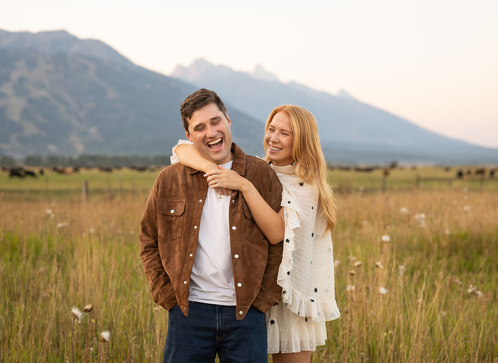 A man laughs as his fiance hugs him from behind.