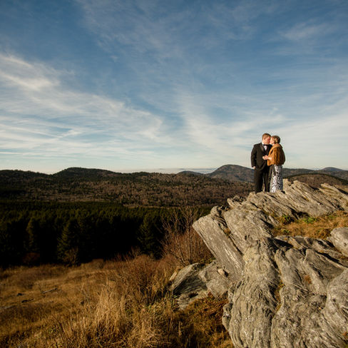 engaged couple standing on the edge of a cliff together 
