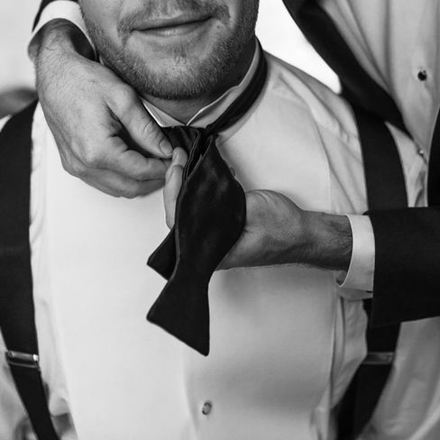 groomsman helping groom with his bowtie