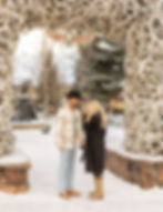 A woman wiping away tears as her fiancé smiles moments after their surprise proposal.