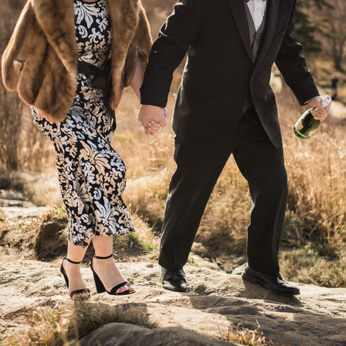 couple's hands and feet walking up a rock 